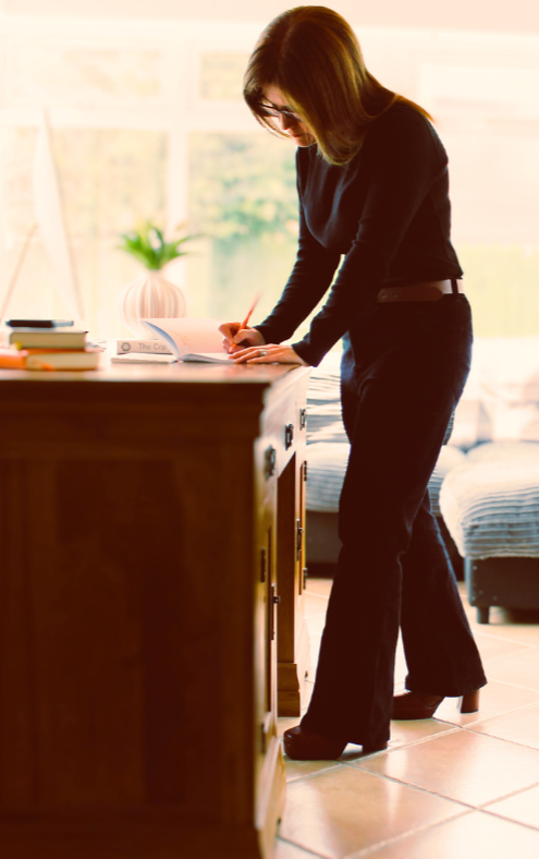 Ciara standing at her desk jotting something down.